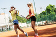A skilled tennis player passionately shares her expertise with a novice, guiding and teaching her techniques on the court.	
