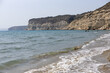 Sandy beach with gentle waves on the Cyprus coast, showcasing cliffs.