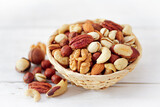 Fototapeta Na sufit - Nuts Mix in a Wooden Plate on a White Background. Wicker Basket full of Cashew, Walnuts, Hazeltuts, Peanuts, Brazilian Nuts, Pistachios