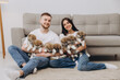 © anatoliycherkas - Beautiful smiling happy couple playing with akita inu puppies in dog house or shelter