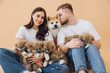 Happy beautiful couple in love caring and playing with little funny puppies and their mother dog on beige background, banner, world animal day, concept: breeding and selling puppies Akita-Inu