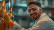 happy young man wearing lab coat and protective goggles working in a pharmaceutical factory