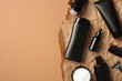 Luxury men's hair care products in black bottles on handmade paper on brown table.