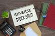 on the work desk there is a red notepad, an envelope, a calculator. text Reverse Stock Split