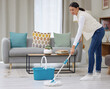 Woman, mop and smile on cleaning floor with home for hygiene, housekeeping and routine. Female person, household and happy with water bucket on day off for chores, fresh in living room or lounge