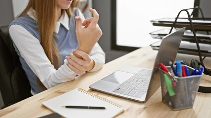 Wall Mural - Young, beautiful blonde business woman in agony from arthritis inflammation, suffering intense hand and finger pain in her office workplace