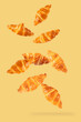 Falling fresh croissant on yellow background.