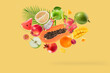 Assortment of different fruits falling on yellow background.