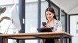 © David - Portrait of young Asian businesswoman in suit, woman smiling and work at workplace inside office, accountant with calculator behind paper phone signing contracts and financial reports