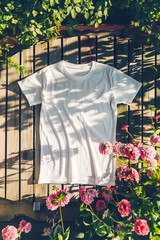 Wall Mural - A white shirt is laying on a wooden fence next to a bush full of pink flowers