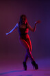 © Pixel-Shot - Beautiful young woman in high heels dancing on dark purple background