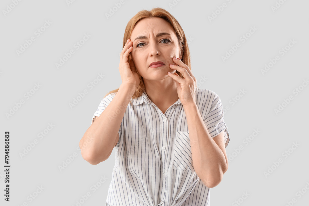 Upset mature woman on light background. Menopause concept