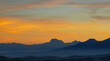 Luminoso tramonto arancio e ocra sopra le montagne italiane
