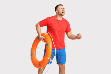 Wall Mural - Happy young lifeguard with lifebuoy running on white background