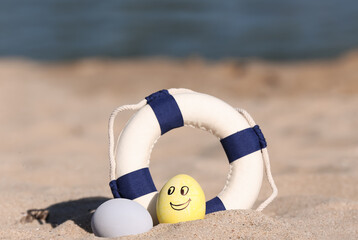 Wall Mural - Painted Easter eggs with lifebuoy on sea beach