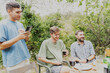 Young men friends spending time at summer party in garden sitting at table, summer, summer weekend in the countryside concept