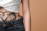 Fototapeta Łazienka - Woman with cool tattoos on beige background, closeup. Space for text