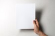 © New Africa - Man holding blank notebook at white table, top view. Mockup for design