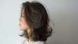 Beautiful asian women's hair with a brown ash color, styled in a curly hairstyle, side view against a white background.