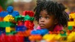 An African American little girl is attentively observing a pile of colorful Legos, engaging in educational playtime