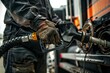 A man is filling up a truck with gas at a gas station. The image focuses on the closeup of his hands gripping the fuel nozzle