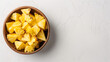 Pineapple chunks in a bowl on a white table aerial view space on the right