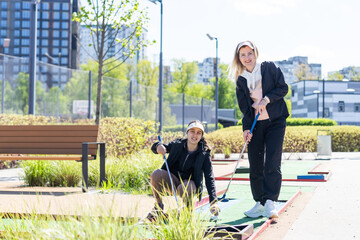 Wall Mural - mother and daughter playing mini golf, children enjoying summer vacation