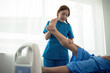 Physical therapist Asian woman, doing leg physiotherapy for elderly man to treat osteoarthritis and nerve pain in the leg to nursing at home and health care concept