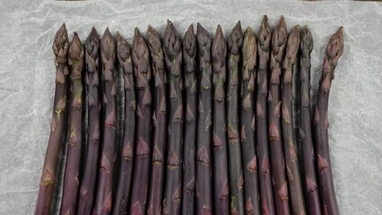 Canvas Print - Heap of fresh purple asparagus bunch in paper from market