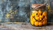   A glass jar, brimming with orange candies, sports a smiling face drawing on its front A string is secured to the jar's top