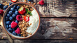 A bowl of yogurt with berries and granola on a wooden table.