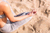 Fototapeta Las - detail of the hand and leg of an unrecognizable woman doing meditation sitting on the beach sand, concept of mental relaxation and healthy lifestyle