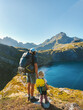 Family father and child with backpack hiking in mountains together exploring Norway adventure healthy lifestyle outdoor active summer vacations dad with daughter enjoying lake view in Lofoten islands