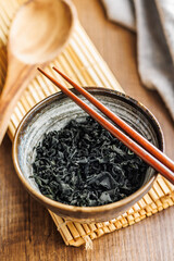 Sticker - Dried wakame seaweed in bowl on wooden table.