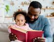 parent and child reading book story young african american man looking book with baby girl
