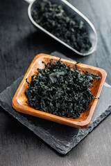 Sticker - Dried wakame seaweed in bowl on black table.