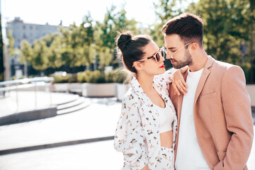 Wall Mural - Beautiful fashion woman and her handsome elegant boyfriend in beige suit. Sexy brunette model in summer clothes. Fashionable smiling couple posing in street Europe. Brutal man and female outdoors