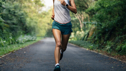 Wall Mural - Sportswoman runner running on tropical park trail