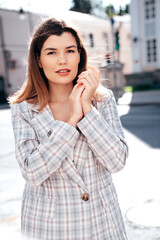 Wall Mural - Portrait of young beautiful brunette woman wearing nice trendy plaid suit jacket. Sexy smiling model posing in the street at sunny day. Fashionable female outdoors. Cheerful and happy.