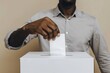 Man in a grey shirt voting by inserting a ballot into a box