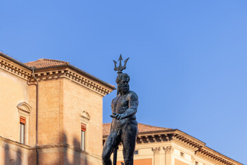 Wall Mural - The imposing Neptune statue dominates the scene at Bologna Fountain of Neptune, crowned with a regal trident against a backdrop of clear blue sky and historic architecture