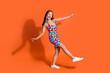 Full length photo of overjoyed good mood woman dressed flower print clothes dancing having fun isolated on orange color background