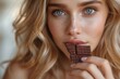 An attractive woman with striking blue eyes bites into a chocolate bar, framing indulgence and beauty in extreme close-up