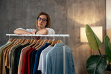 Fototapeta Tulipany - Fashion boutique owner with arms on clothing rack