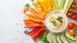 A colorful assortment of fresh vegetable crudites with hummus dip, providing a healthy and appetizing snack or appetizer choice on a clean white surface.