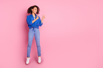 Sticker - Photo of positive cheerful girl wear stylish blue clothes jump up introduce empty space isolated on pink color background