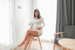 Pregnant Asian woman in white dress in bedroom
