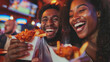 Close-up of a couple's cheerful expressions as they dig into chicken wings and fries at a sports bar, their enthusiasm adding to the energetic vibe of the bustling eatery.