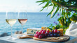 White and rose wine in glasses, appetizers and grapes on a wooden table overlooking the seashore