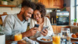 © Dina Photo Stories - Millennial afro-american Man And Woman Having Breakfast And Using Smartphone In Kitchen, Happy Couple Browsing Internet On Mobile Phone While Eating Tasty Food At Home Together. Food delivery app